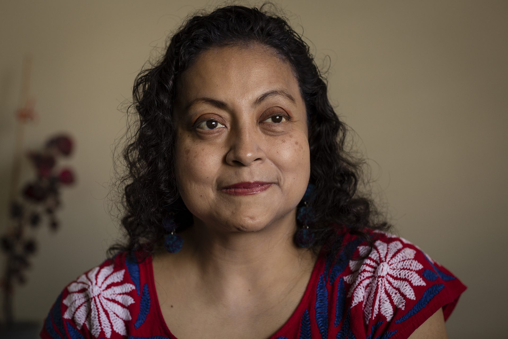 close image of Julieta Alcántar-García wearing a red top with shite flowers and blue accents