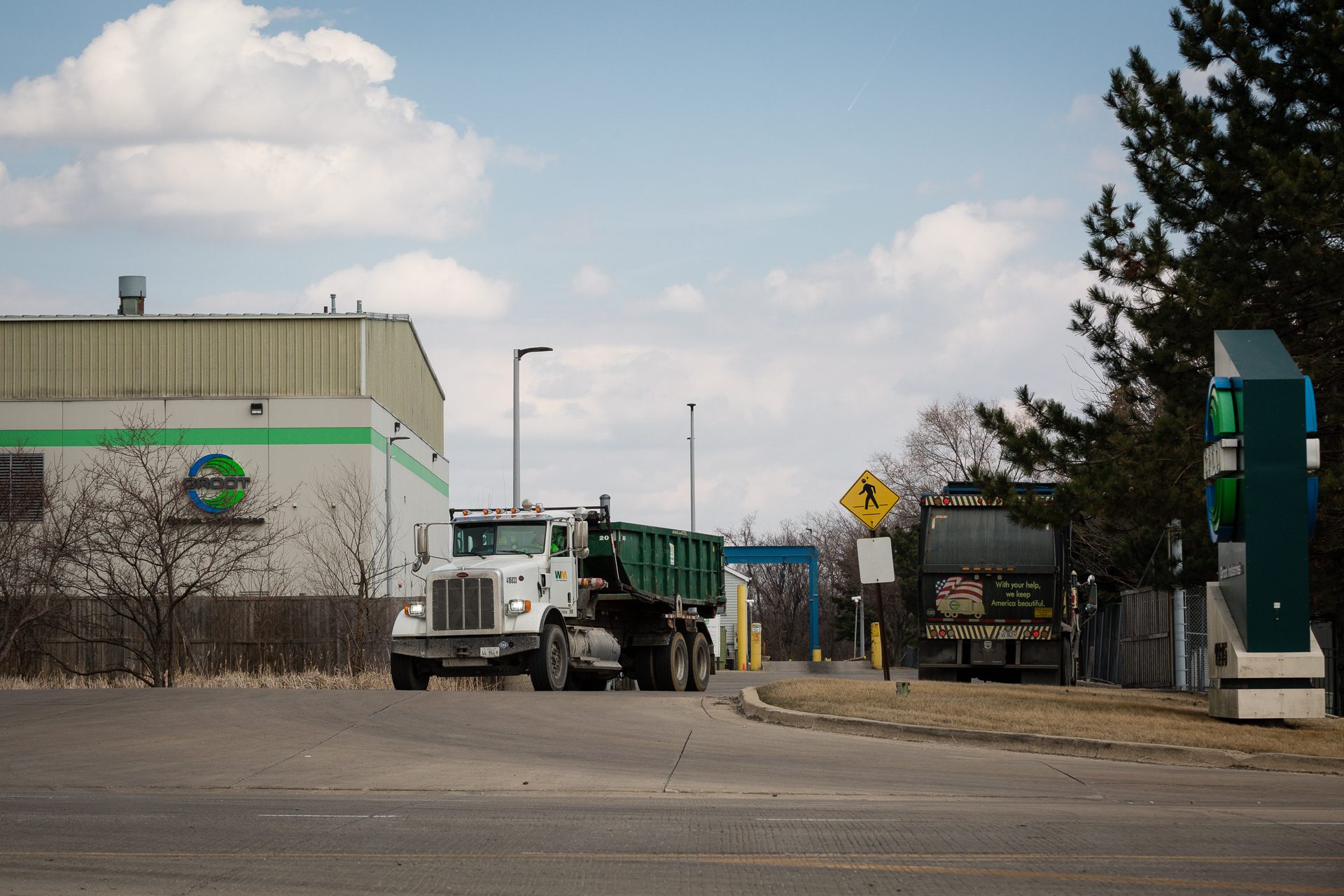 Un camión de basura Groot sale de la instalación de transferencia de residuos mientras otro entra