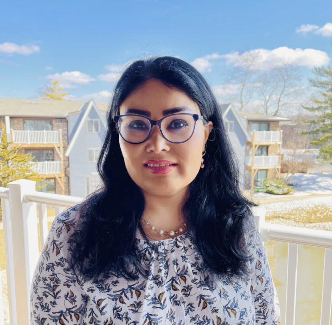 An image of an Afghan female journalist wearing glasses and on a balcony