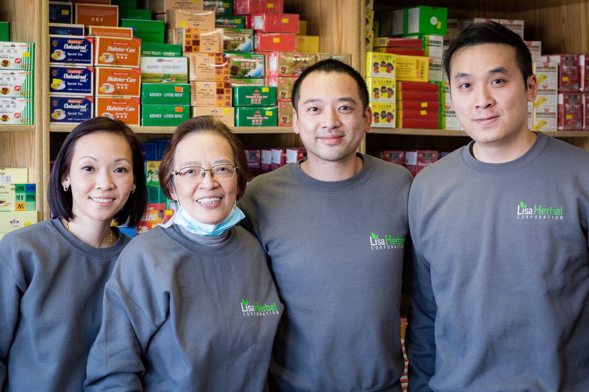 Lisa Lau y sus hijos frente a una pared de cajas de té