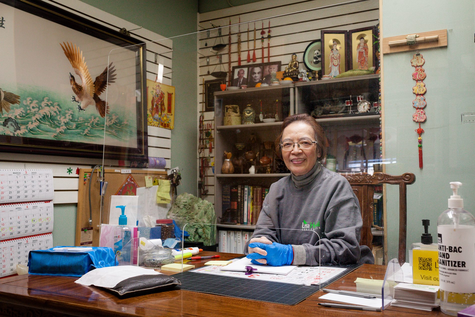 Lisa Lau in her office behind a plastic divider looking at the camera