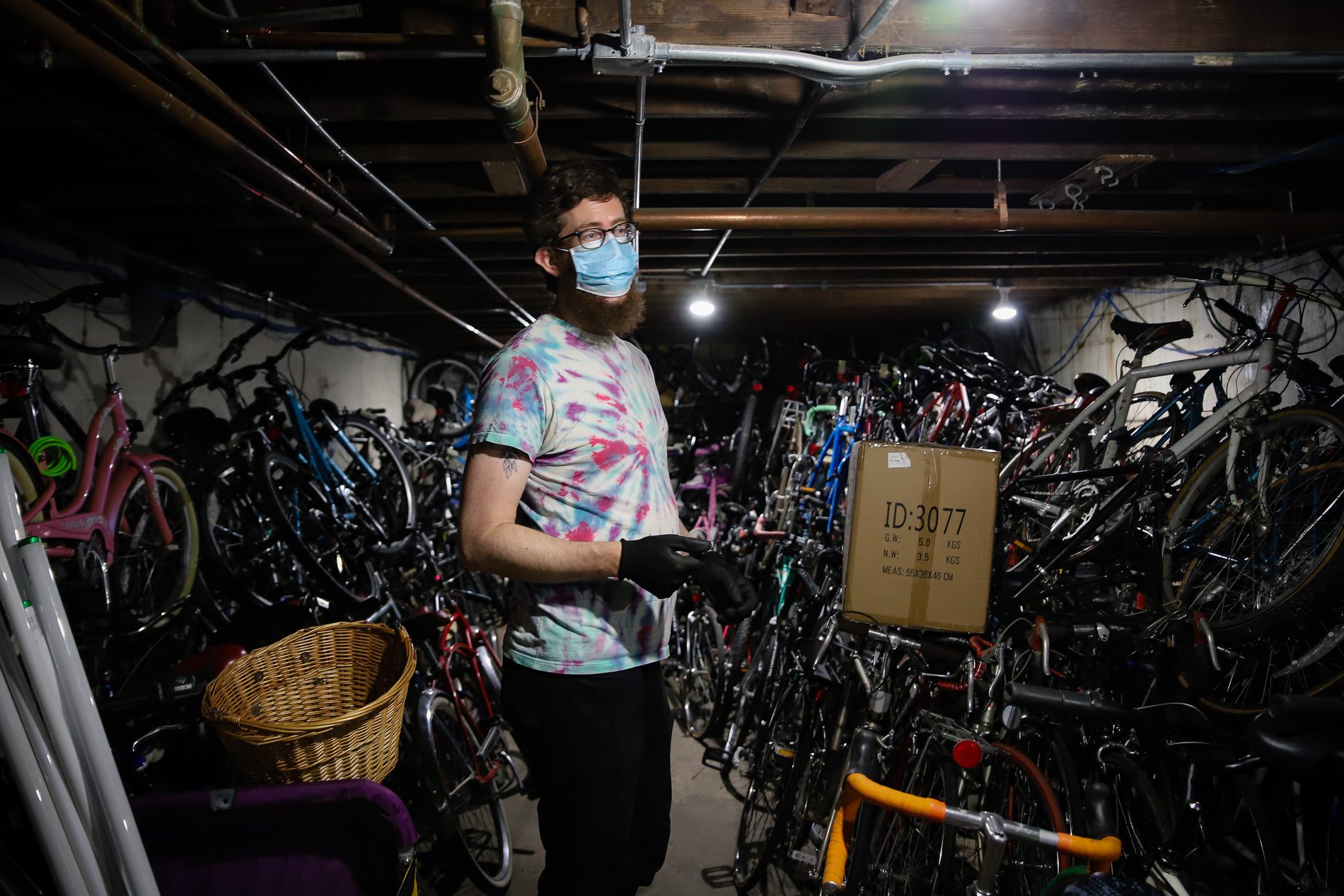 Dana Smith surrounded by bicycles piled up to the ceiling of a basement