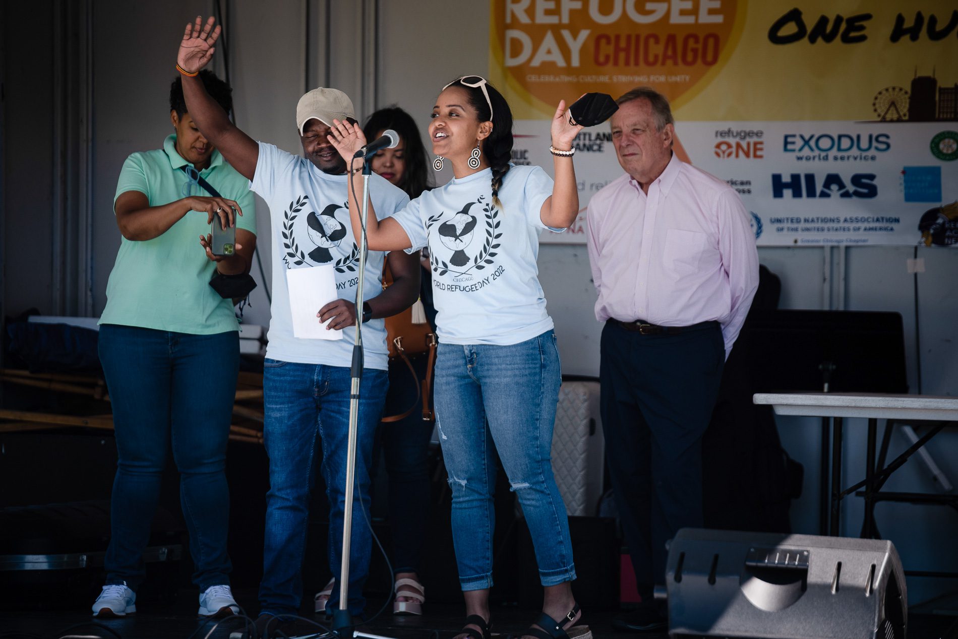 Rebkah Zellelew speaks on a stage and raises her hands