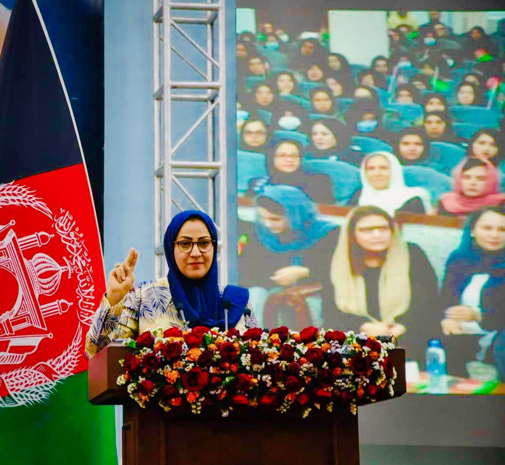 Naheed Farid at a podium with flowers