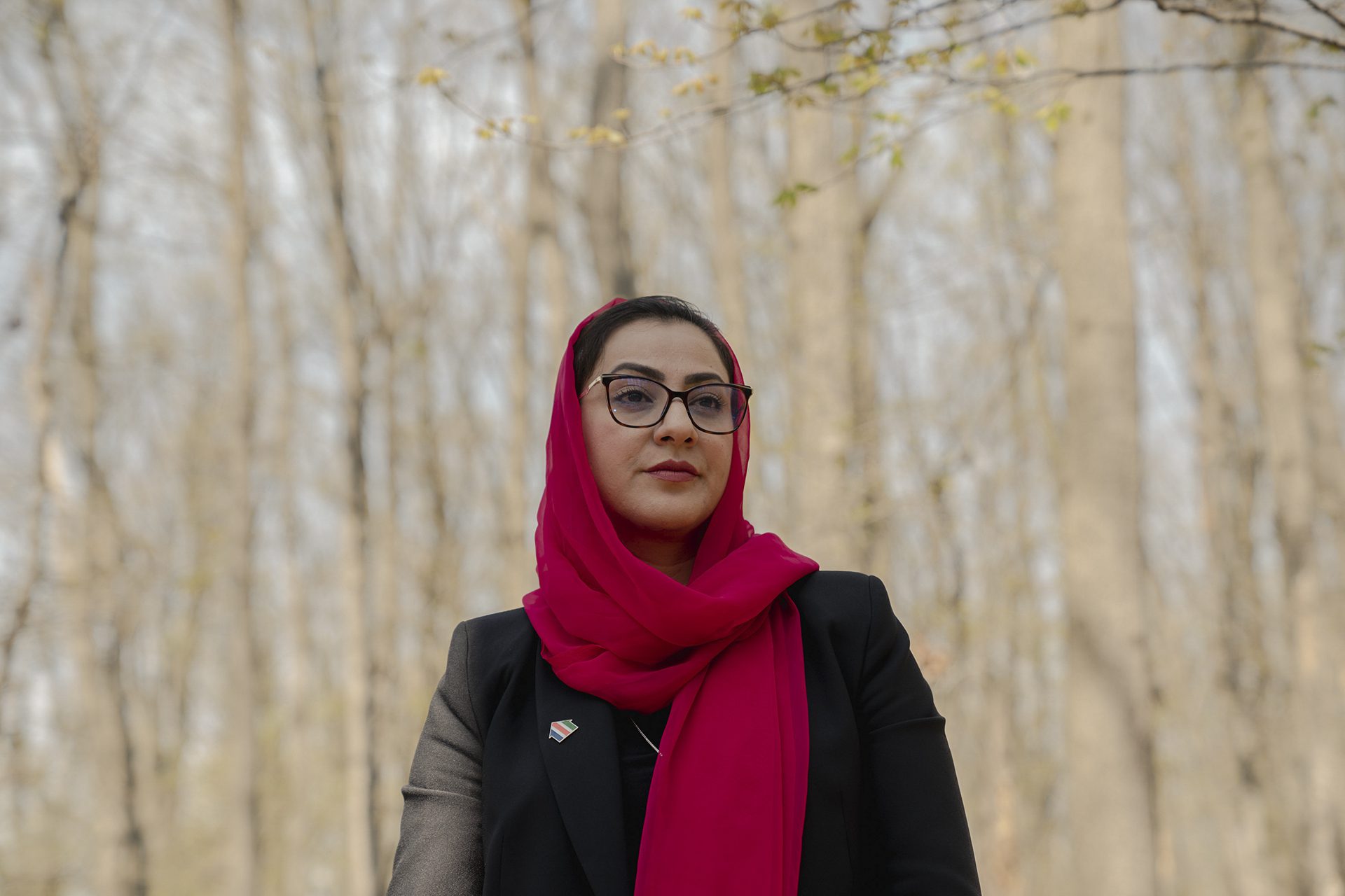 Naheed Farid con un pañuelo rojo y árboles detrás de ella