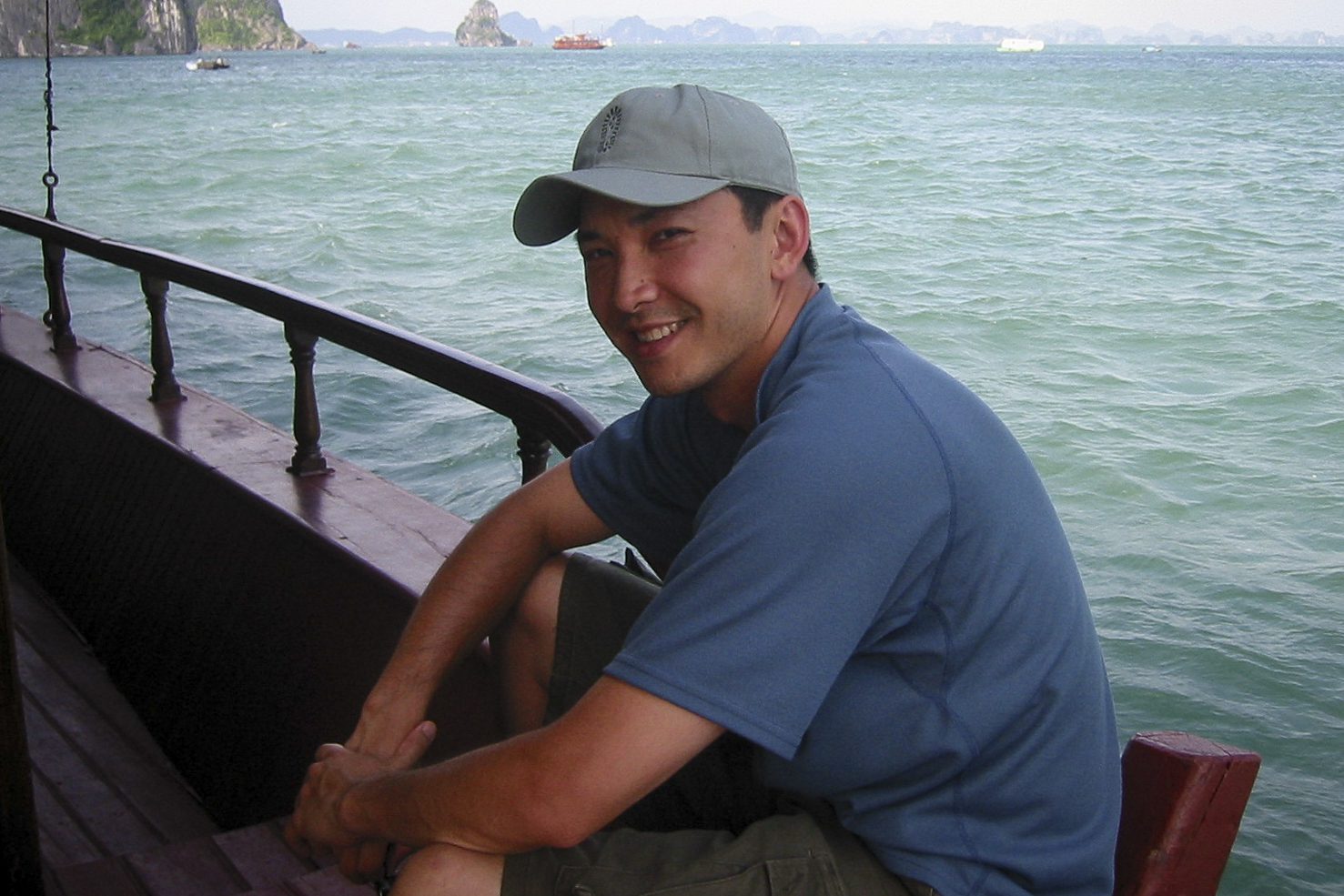 Viet Thanh Nguyen in Ha Long Bay on a red boat wearing a blue hat