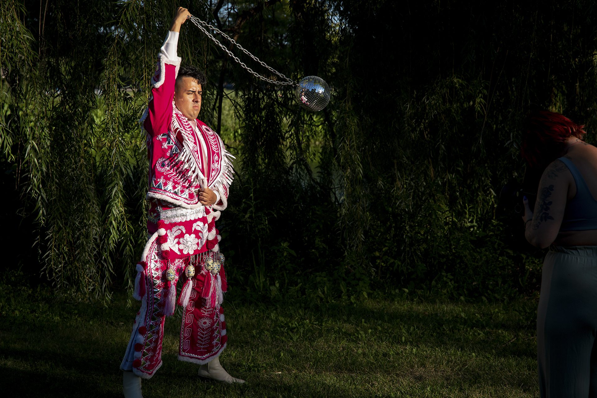 J Saxon swings a disco ball dressed in a traditional pink Bolivian suit