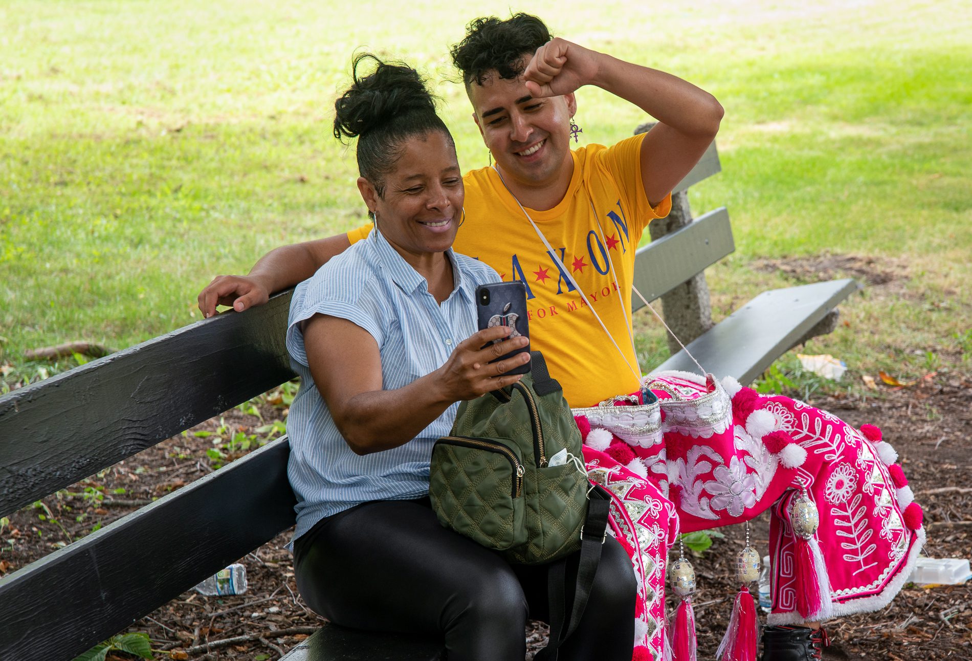 Regina Johnson poses for a photograph with J Saxon on a park bench with J.'s fist raised