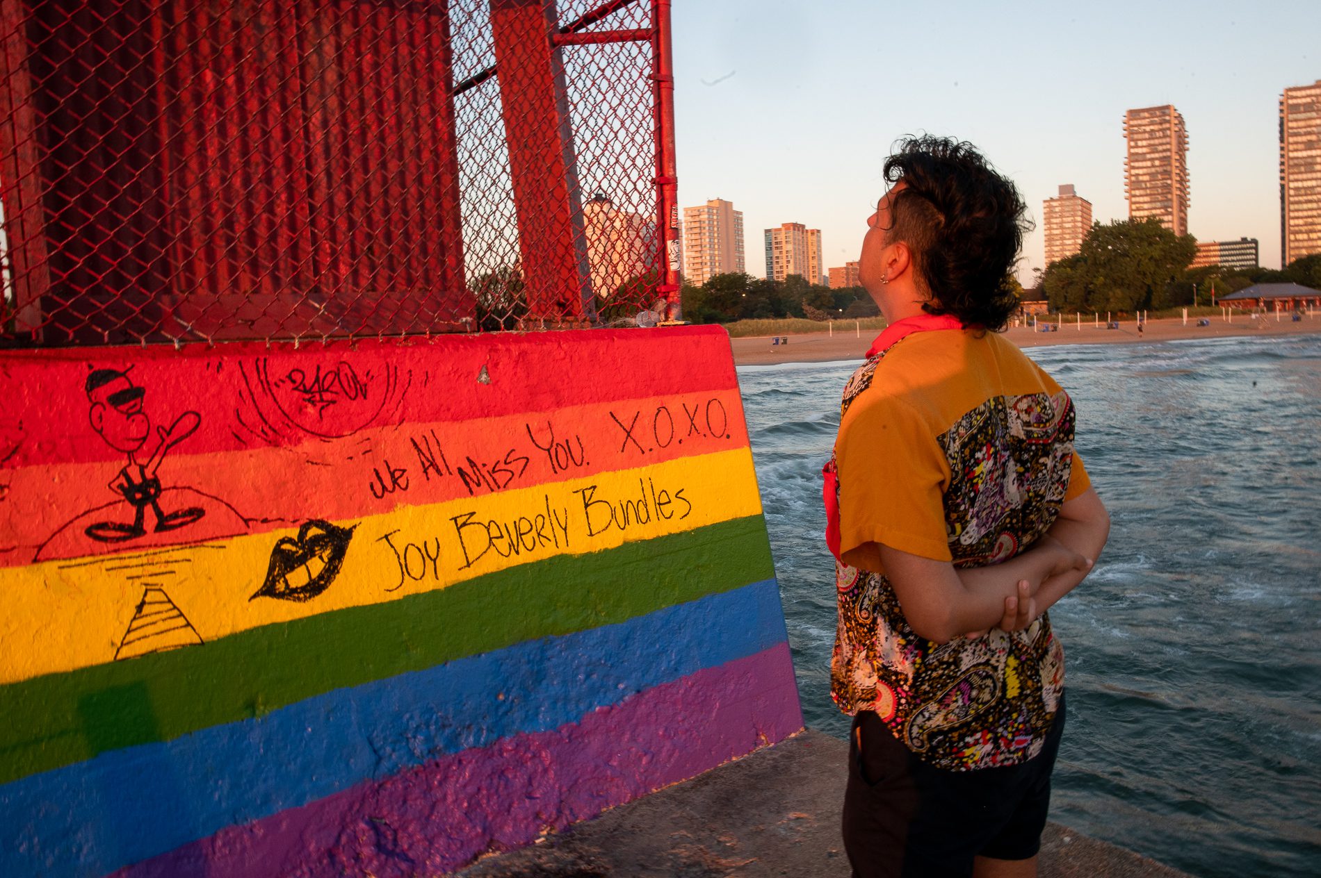 J. Saxon looks at a mural dedicated to their late friend, Joy Beverly Bundles, at Hollywood Beach Pier. THe mural has rainbow colors and say "We all miss you"