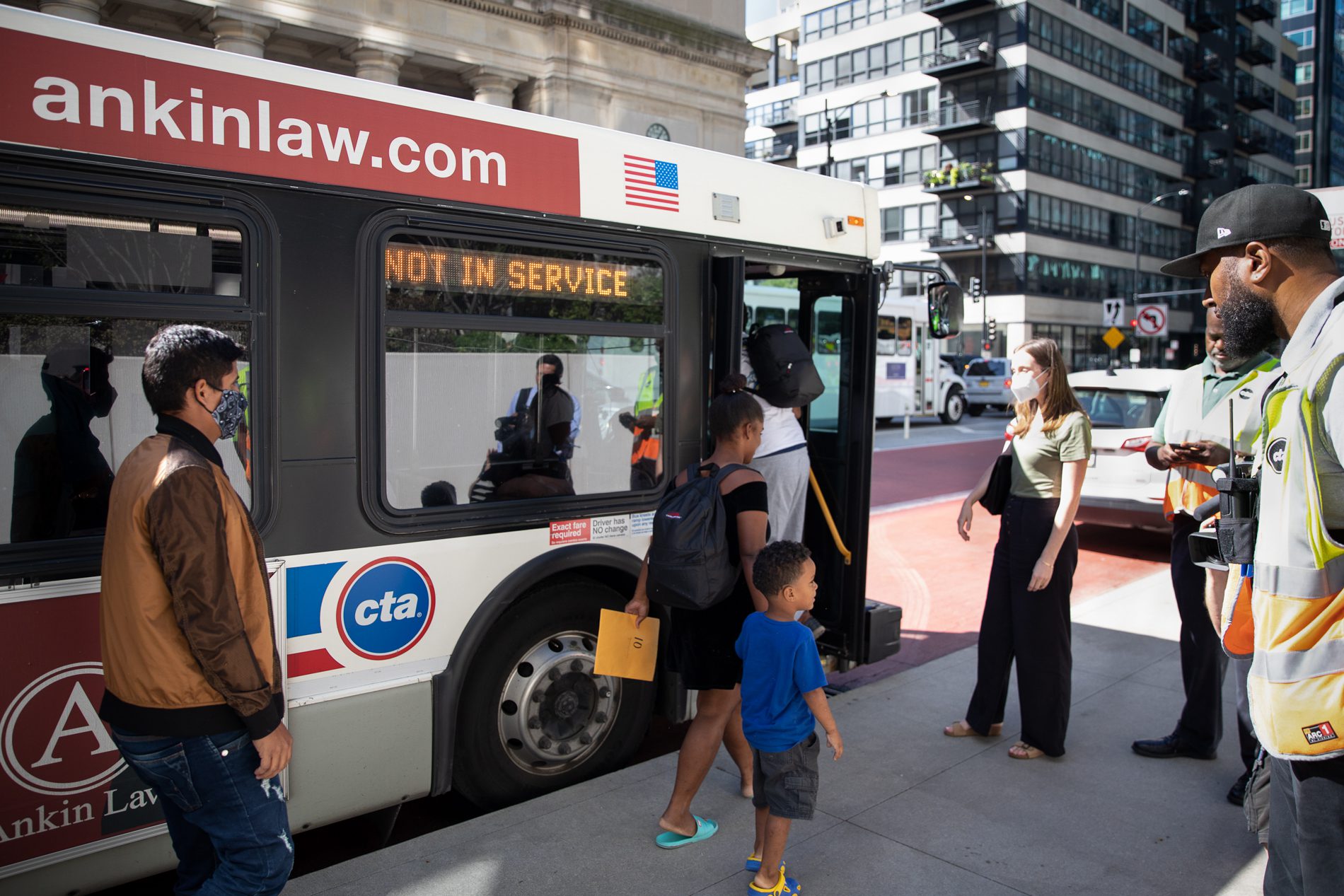 Migrants walk to a city bus after being sent to Chicago from Texas by Gov. Greg Abbott