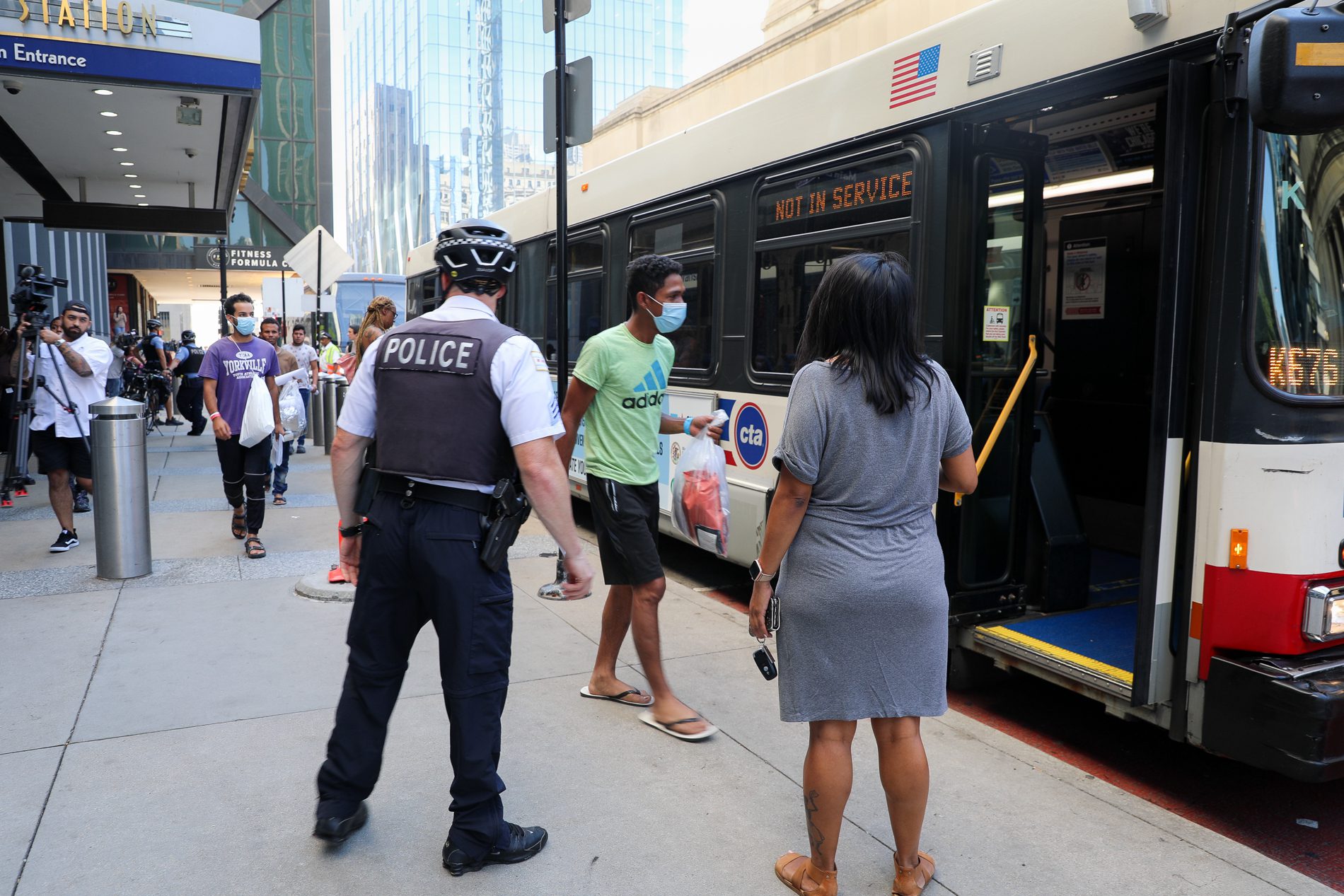 Migrants walk to a city bus after being sent to Chicago from Texas by Gov. Greg Abbott