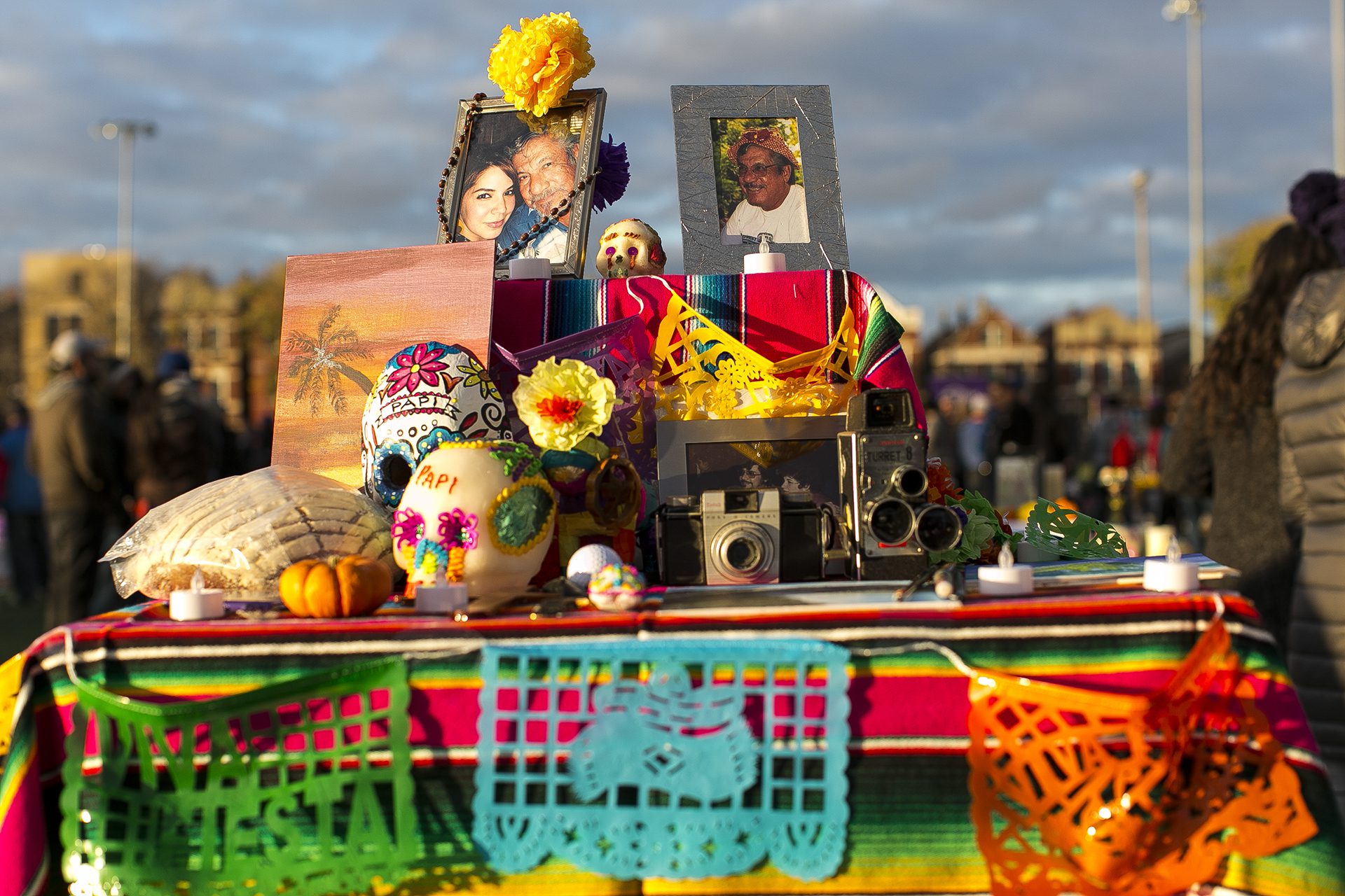 Ofrenda del Día de los Muertos con fotos, cámaras, velas, conchas, banderas y calaveras de azúcar