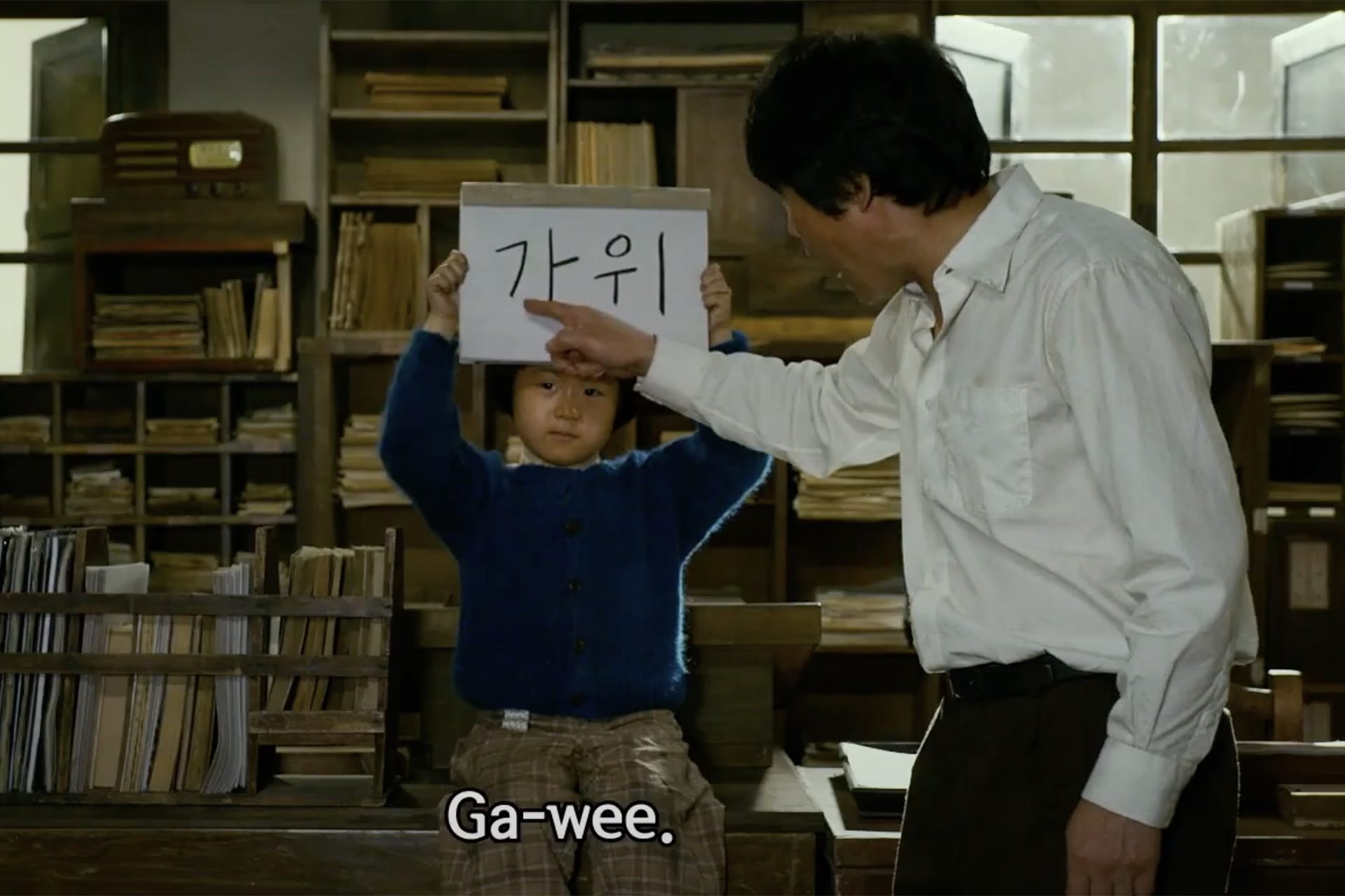 una chica sostiene un cartel en coreano y un hombre lo señala