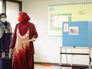 Una mujer con un hijab rojo vota