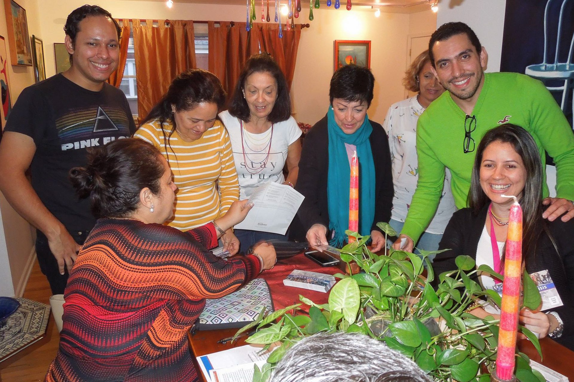 Eight people gathered around a table handing out information and smiling