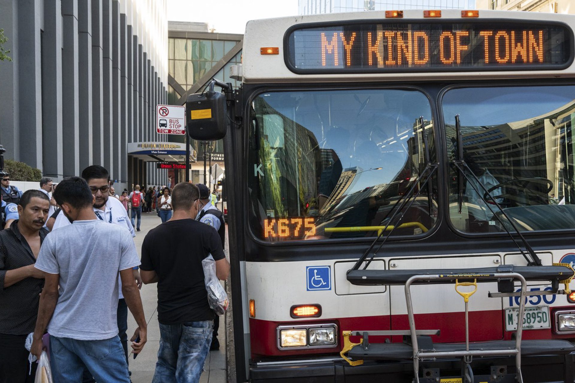 migrants by a Chicago bus that says "my kind of town"