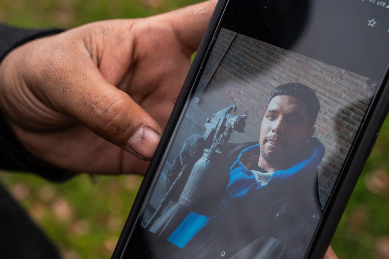 A picture of Nolram wearing a blue hoodie and holding equipment with a brick background behind him