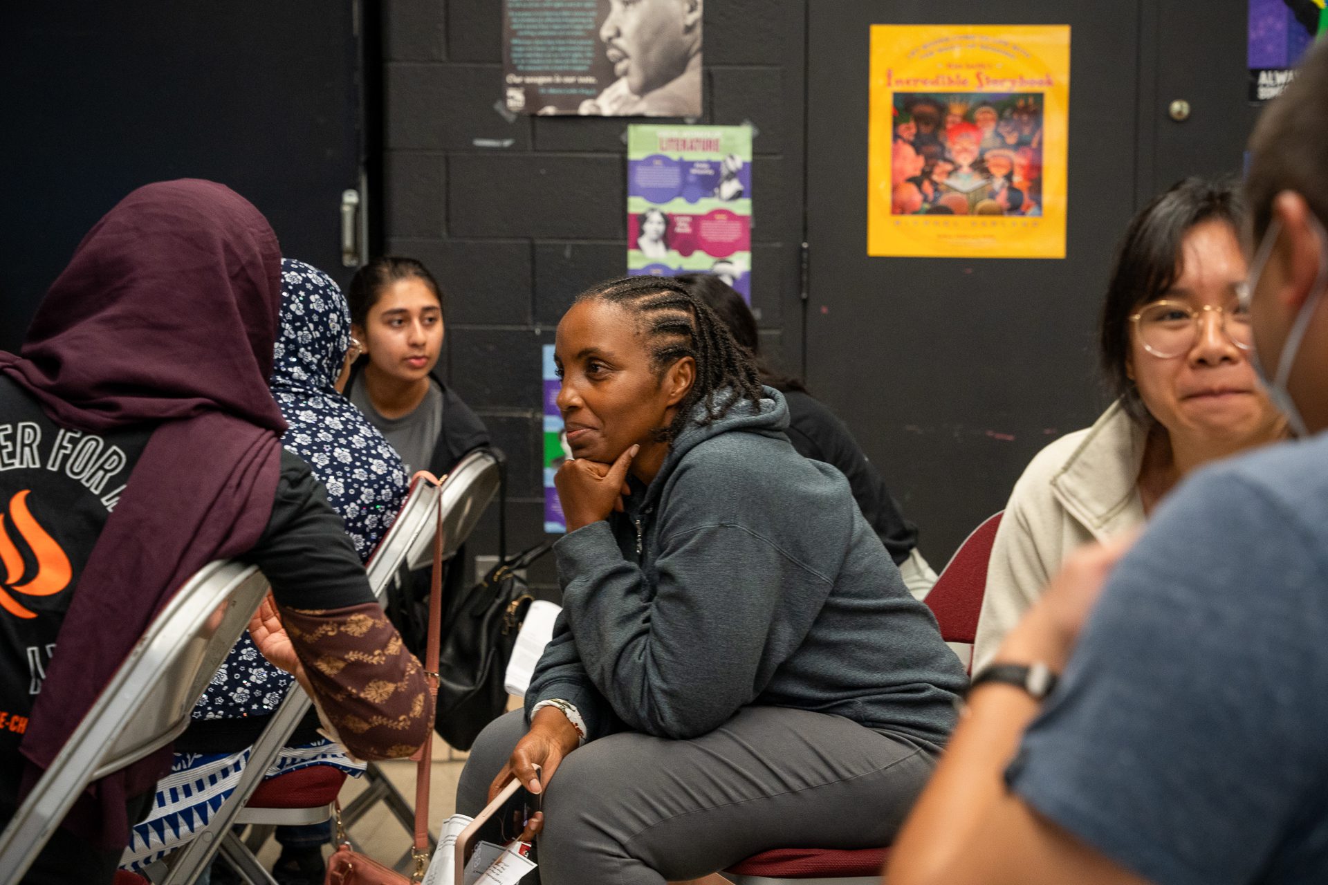 A woman sitting in a chair listens intently to another person during a town hall to discuss a language access bill making its way through Illinois.