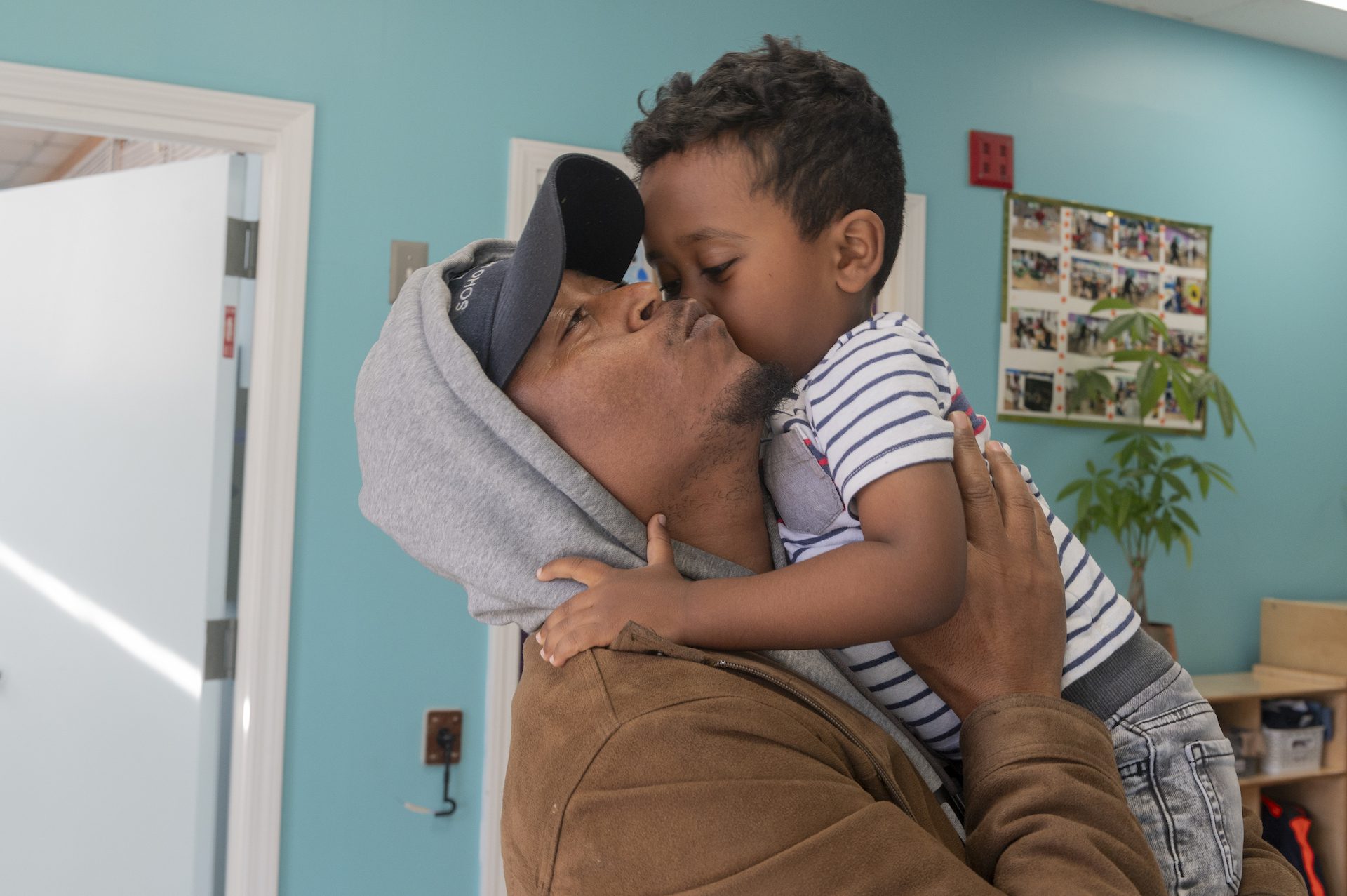 A man picks up his three-year-old son from daycare.